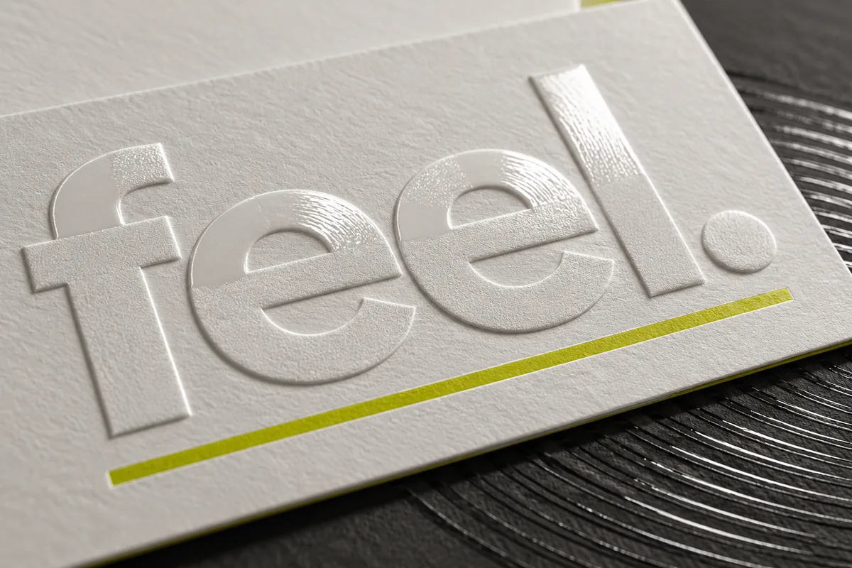 Concept image of the word feel in raised white lettering on a white card, underlined in lime